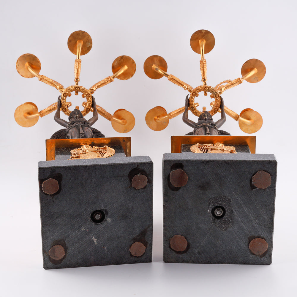 A collection of four gilt bronze candelabras adorned with bronze winged Victory sculptures