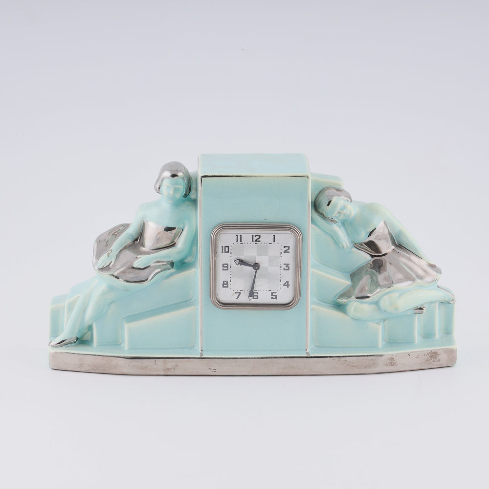 Reloj Fajance Art Deco con forma de pedestal y dos elegantes bailarinas sentadas con gracia a cada lado.