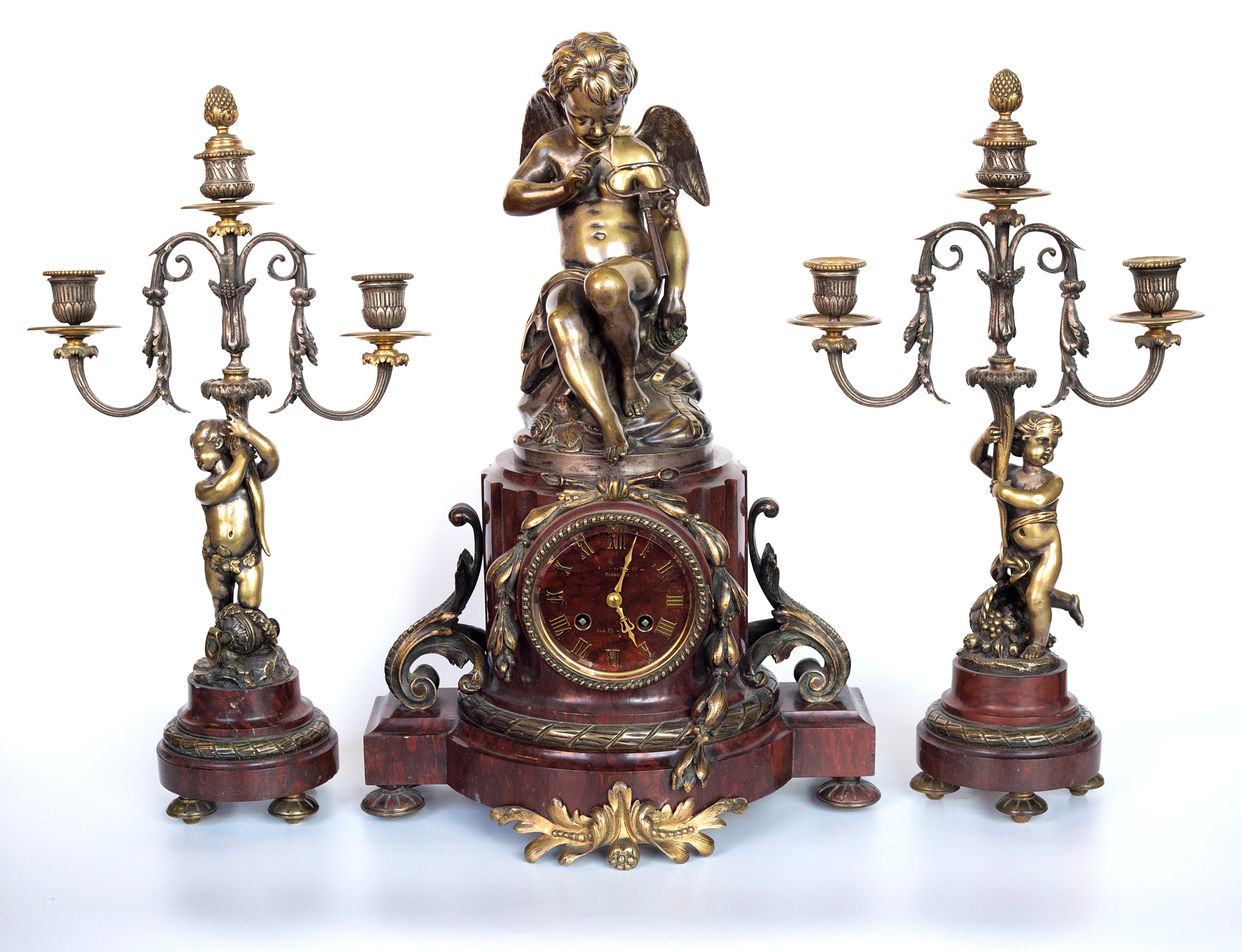 Antique handcrafted bronze clock sits atop a stone plinth, featuring a sculpture of a Putti, inspired by the French Rococo sculptor Clodion (Claude Michel)