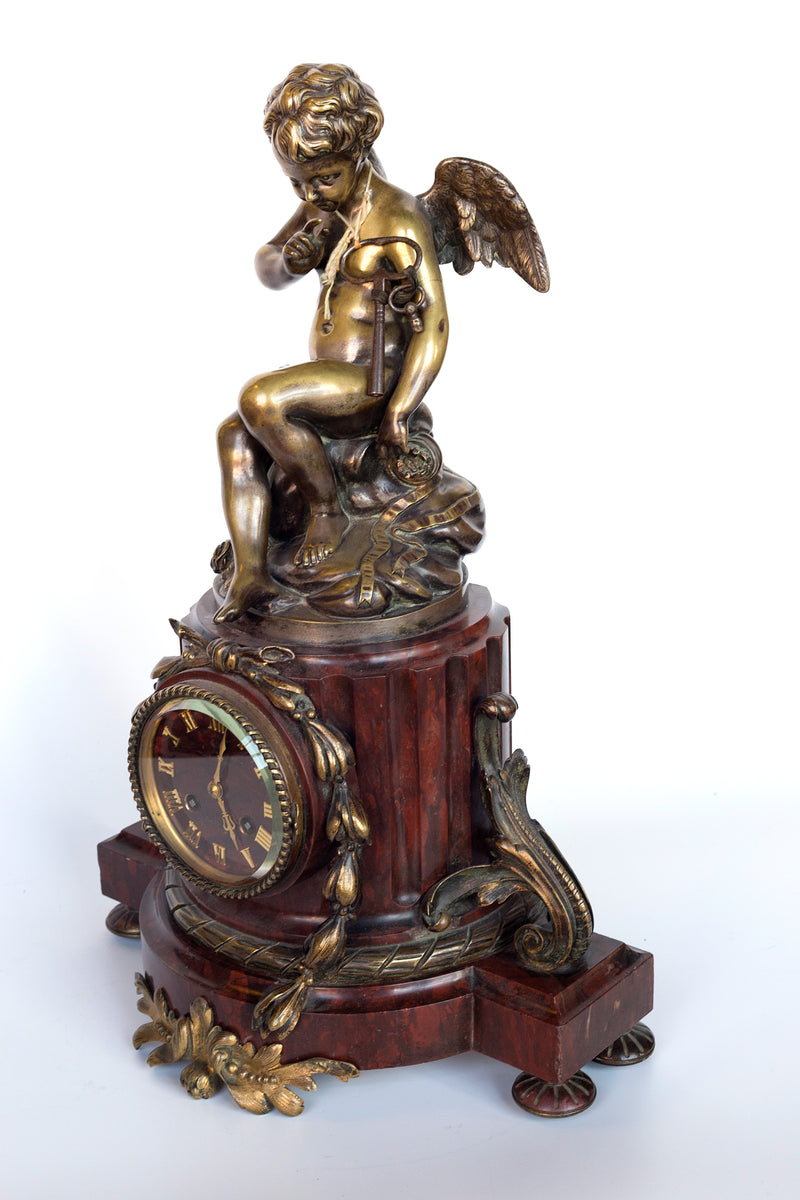 Antique handcrafted bronze clock sits atop a stone plinth, featuring a sculpture of a Putti, inspired by the French Rococo sculptor Clodion (Claude Michel)