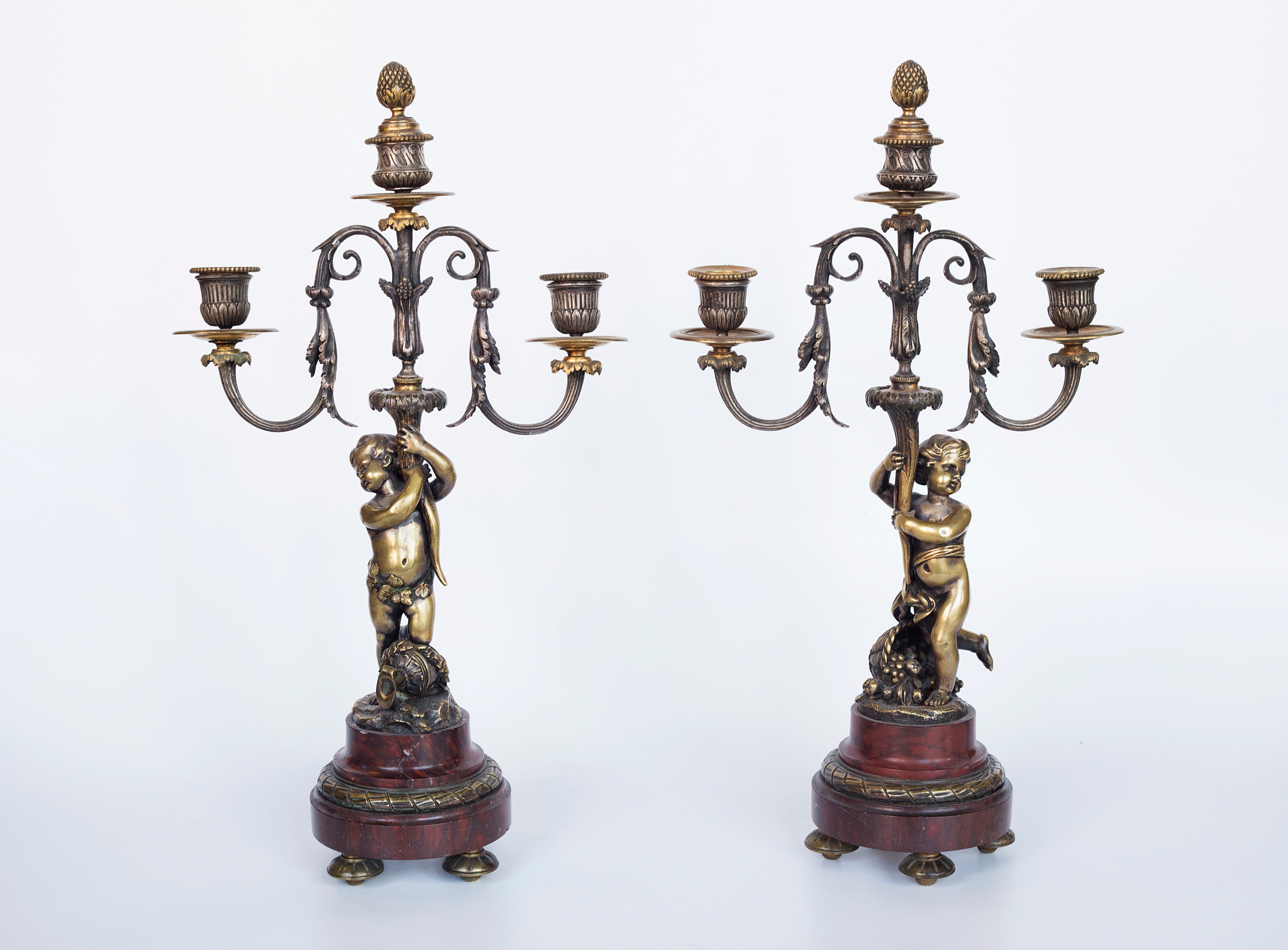 Antique handcrafted bronze clock sits atop a stone plinth, featuring a sculpture of a Putti, inspired by the French Rococo sculptor Clodion (Claude Michel)