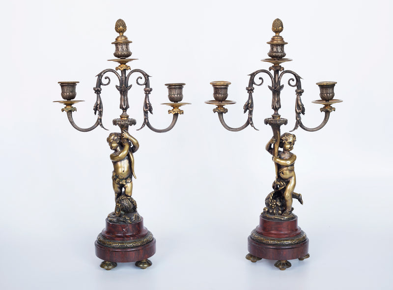 Antique handcrafted bronze clock sits atop a stone plinth, featuring a sculpture of a Putti, inspired by the French Rococo sculptor Clodion (Claude Michel)