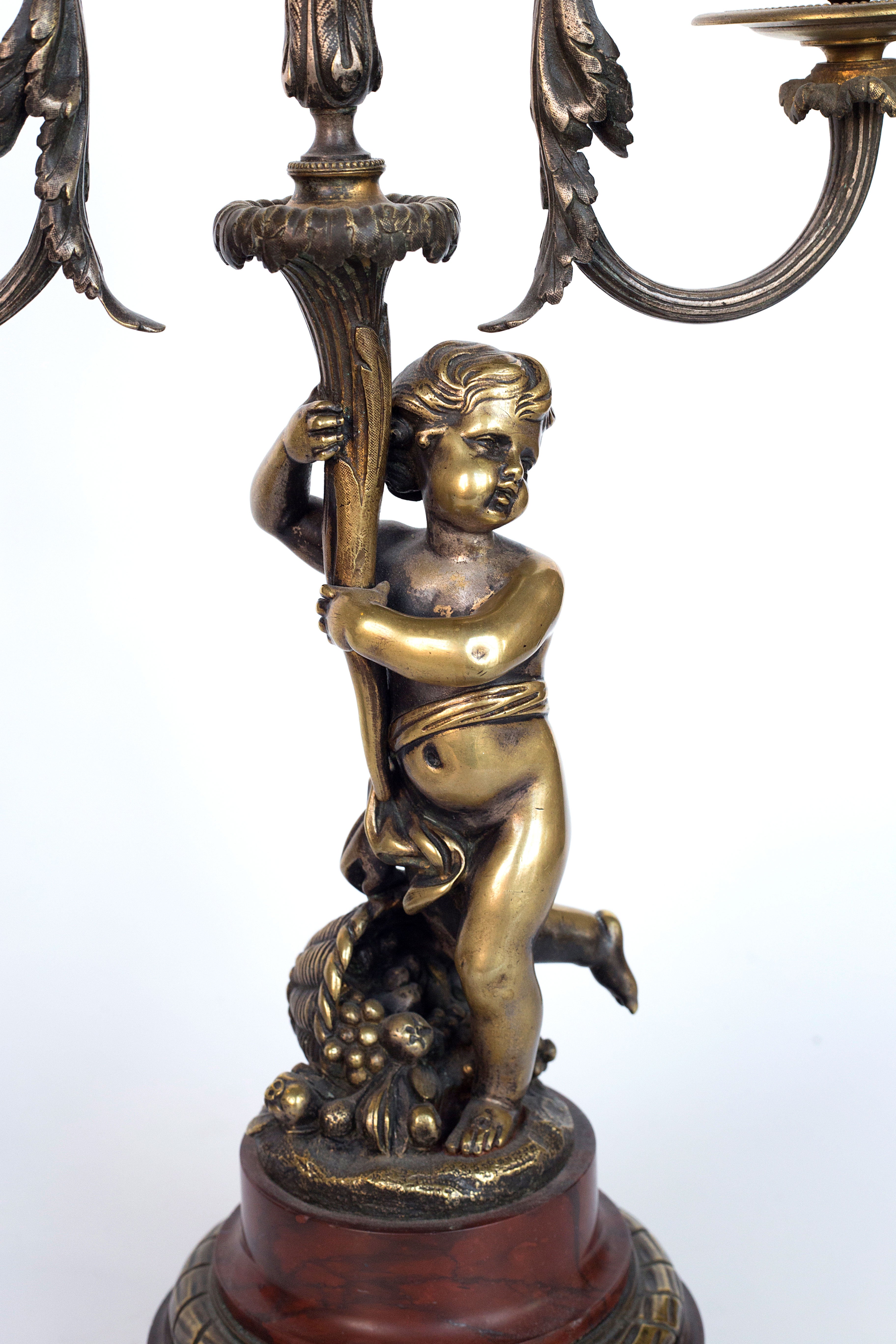 Antique handcrafted bronze clock sits atop a stone plinth, featuring a sculpture of a Putti, inspired by the French Rococo sculptor Clodion (Claude Michel)