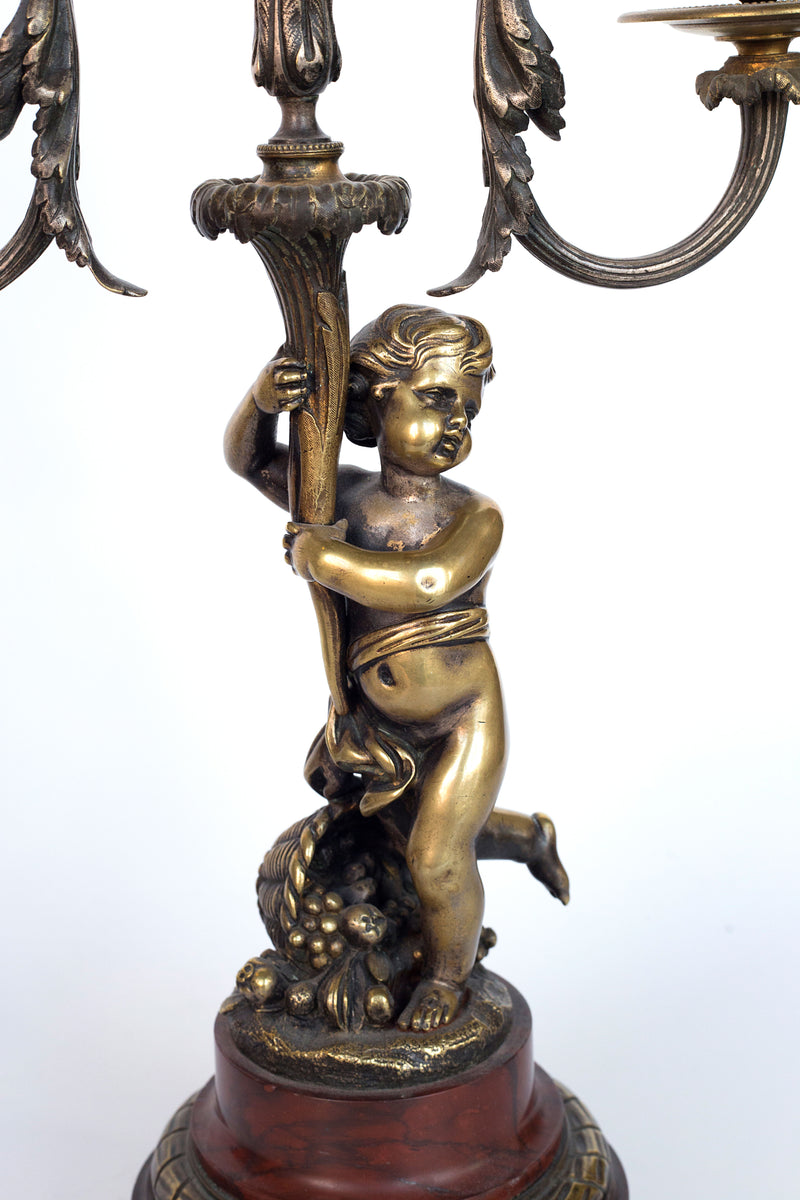 Antique handcrafted bronze clock sits atop a stone plinth, featuring a sculpture of a Putti, inspired by the French Rococo sculptor Clodion (Claude Michel)