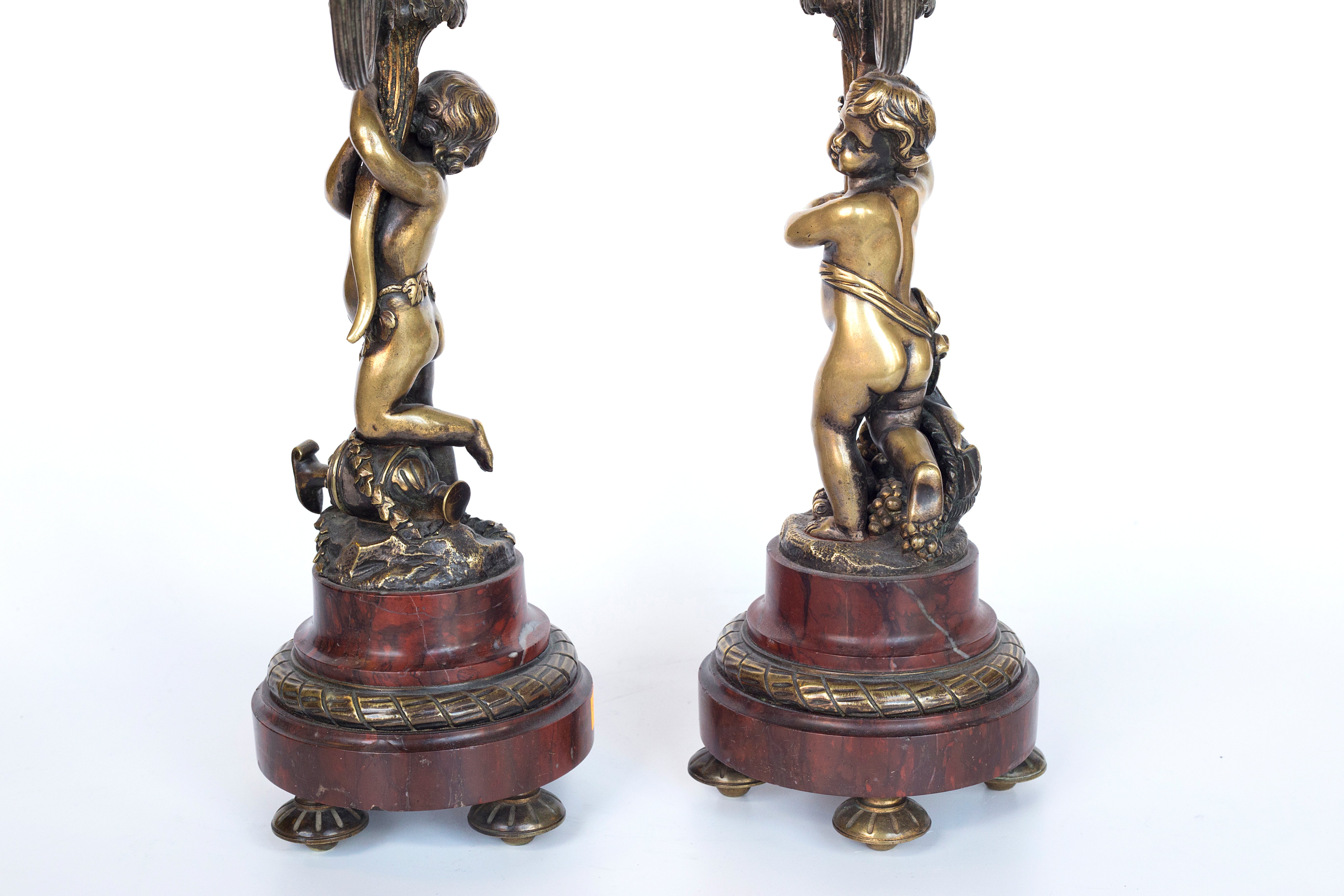 Antique handcrafted bronze clock sits atop a stone plinth, featuring a sculpture of a Putti, inspired by the French Rococo sculptor Clodion (Claude Michel)