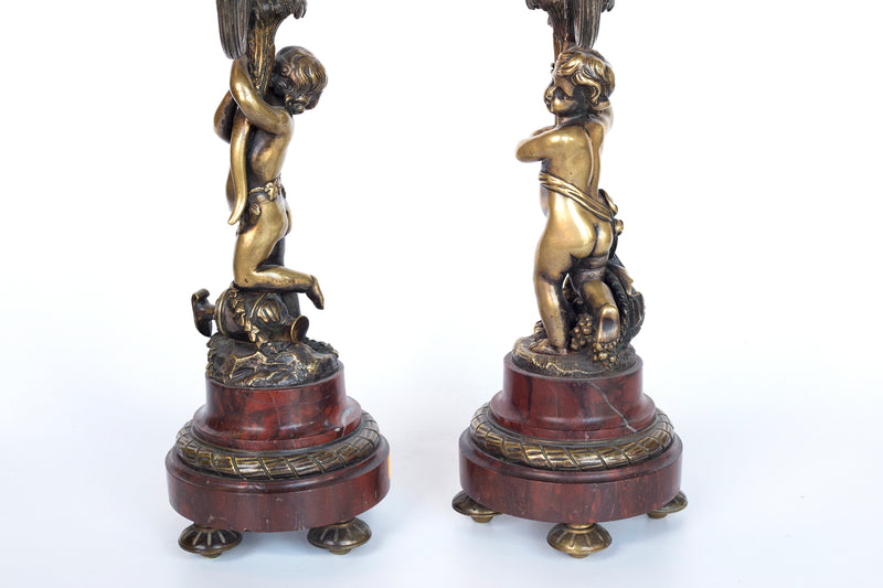 Antique handcrafted bronze clock sits atop a stone plinth, featuring a sculpture of a Putti, inspired by the French Rococo sculptor Clodion (Claude Michel)