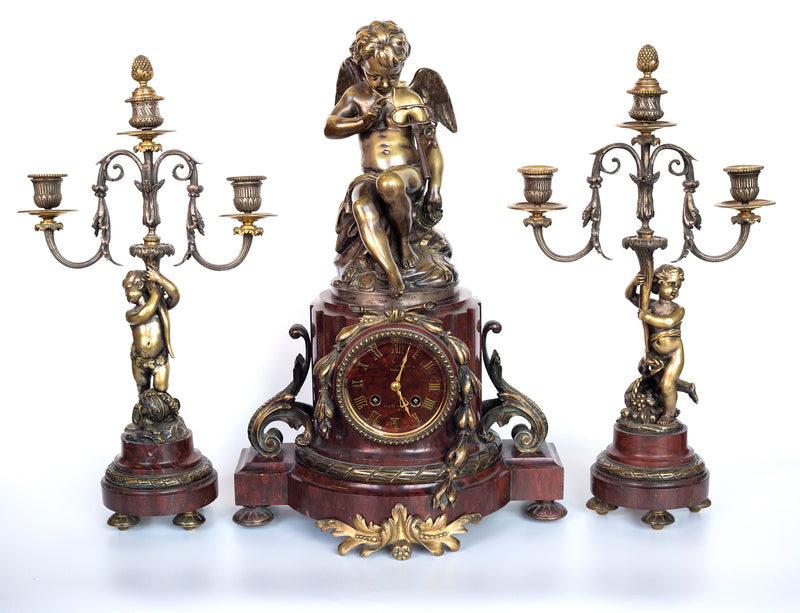 Antique handcrafted bronze clock sits atop a stone plinth, featuring a sculpture of a Putti, inspired by the French Rococo sculptor Clodion (Claude Michel)