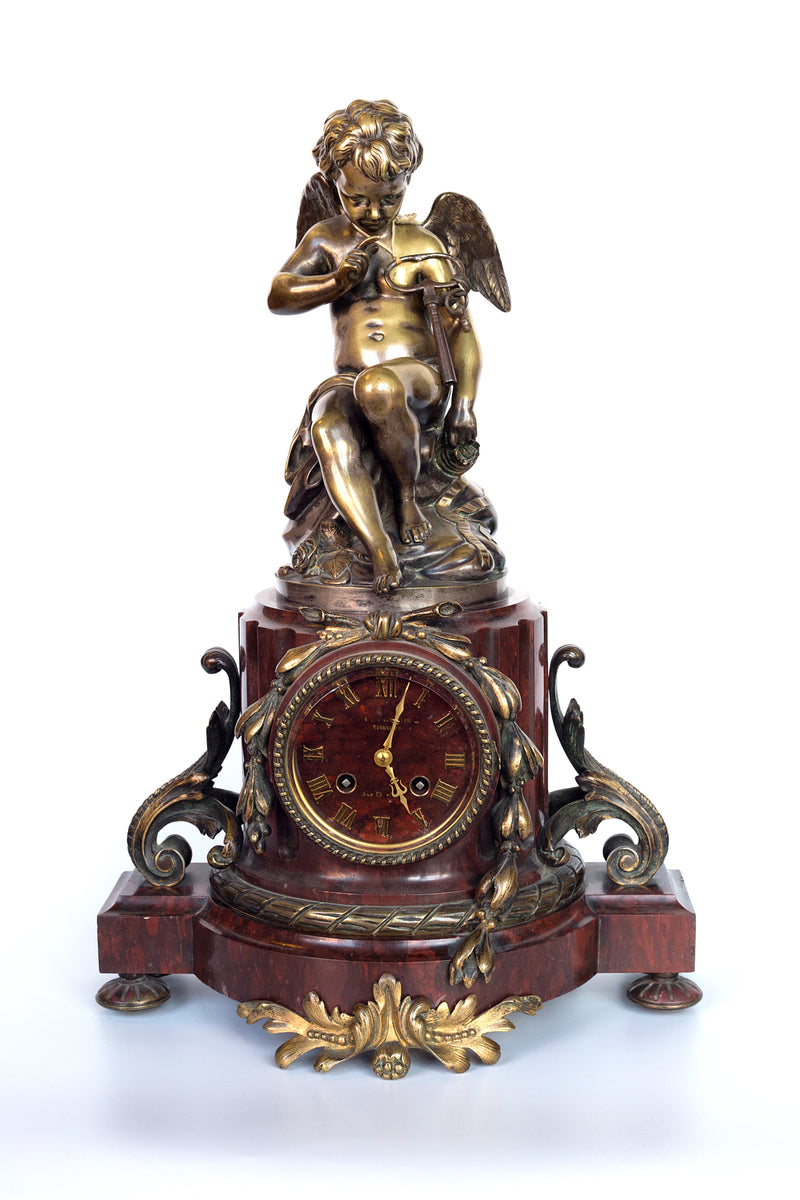Antique handcrafted bronze clock sits atop a stone plinth, featuring a sculpture of a Putti, inspired by the French Rococo sculptor Clodion (Claude Michel)