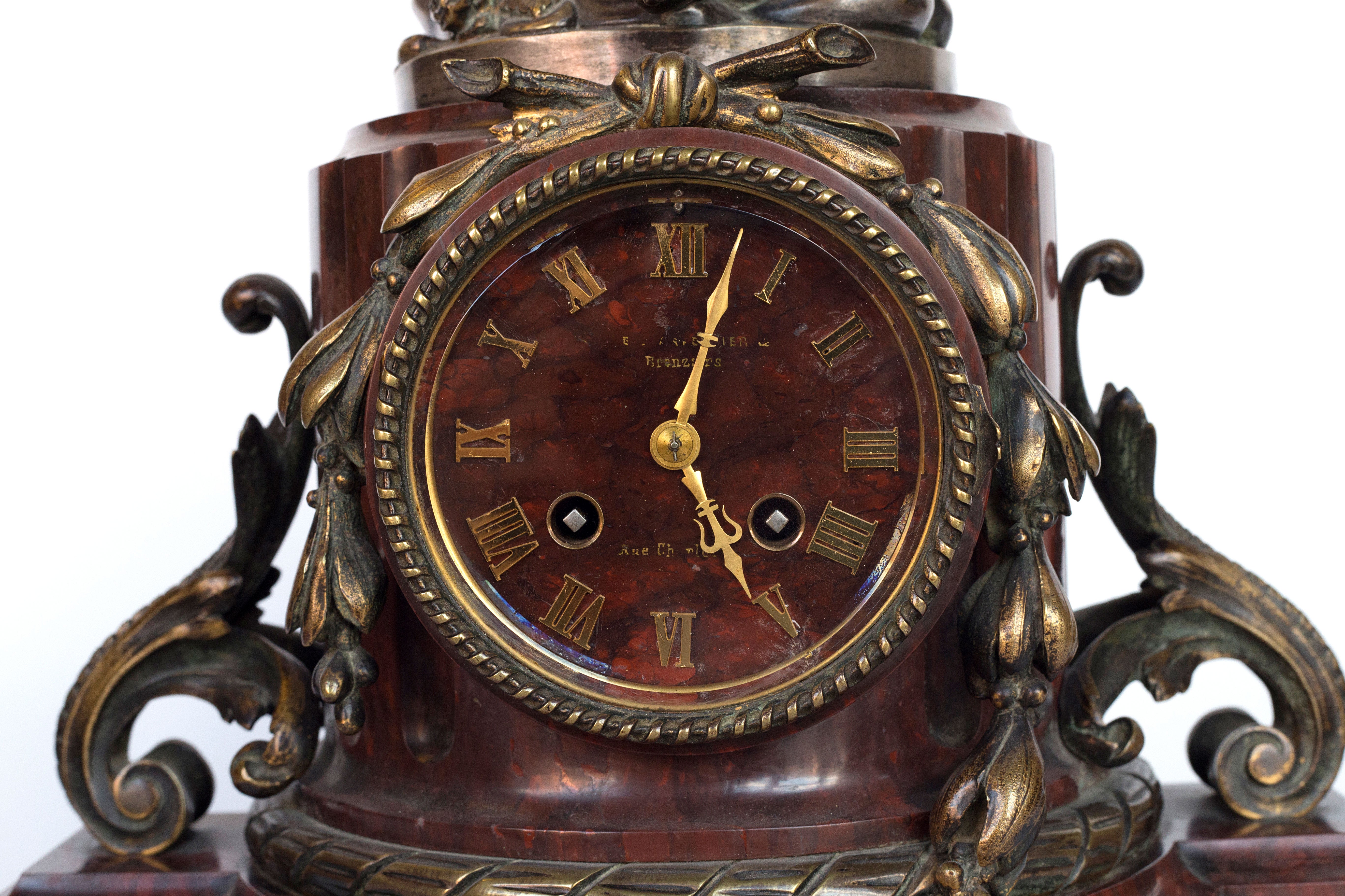 Antique handcrafted bronze clock sits atop a stone plinth, featuring a sculpture of a Putti, inspired by the French Rococo sculptor Clodion (Claude Michel)