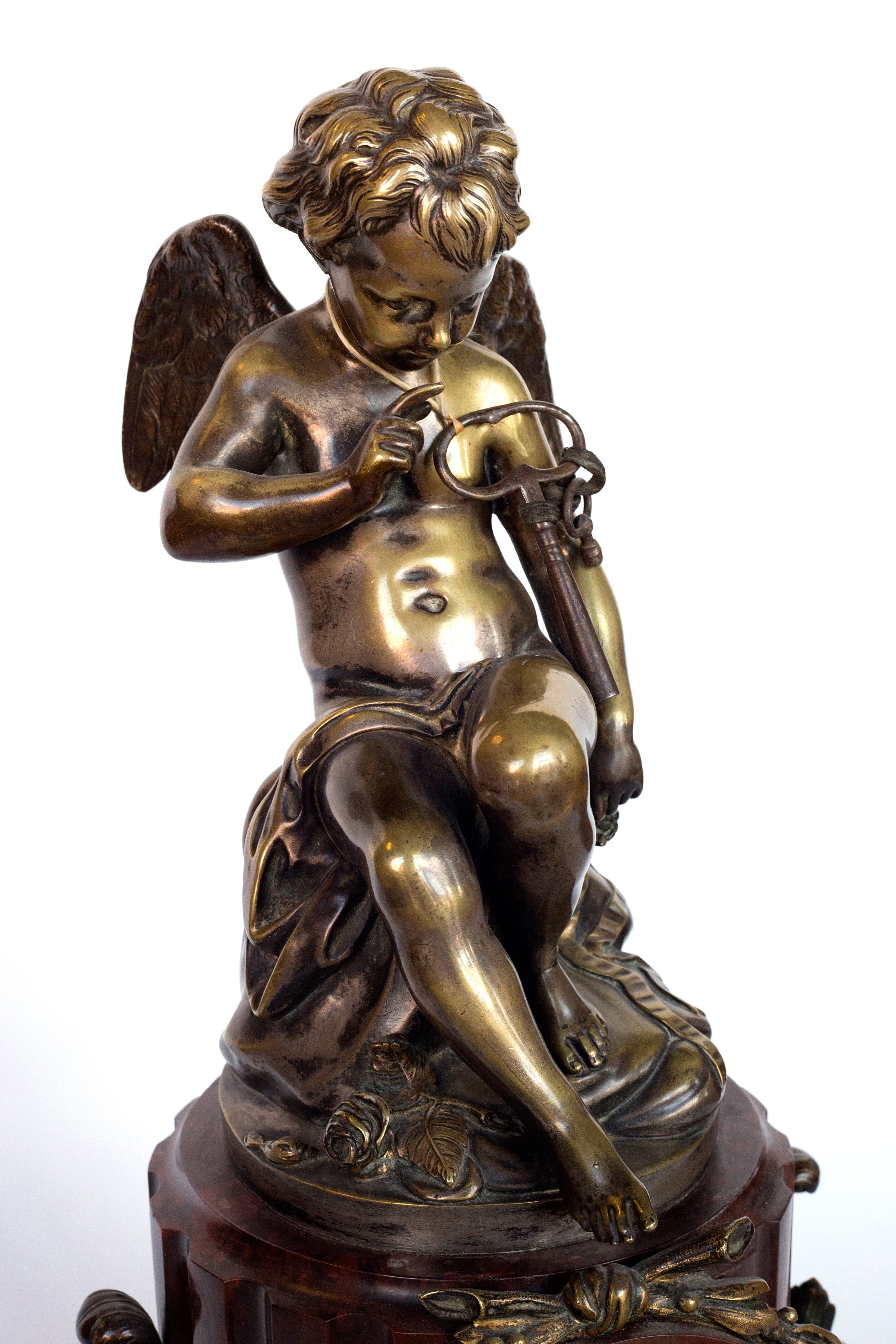 Antique handcrafted bronze clock sits atop a stone plinth, featuring a sculpture of a Putti, inspired by the French Rococo sculptor Clodion (Claude Michel)