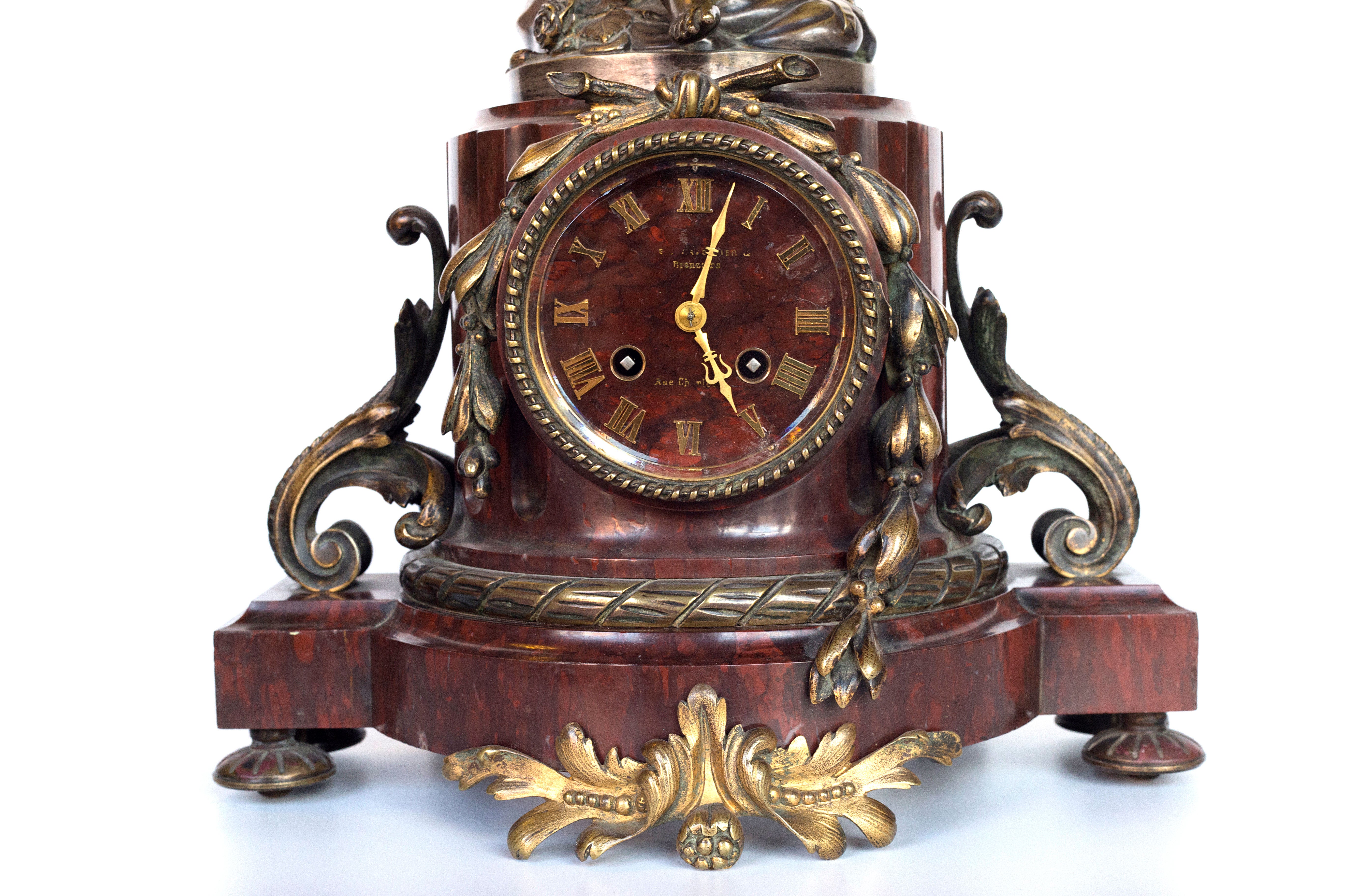 Antique handcrafted bronze clock sits atop a stone plinth, featuring a sculpture of a Putti, inspired by the French Rococo sculptor Clodion (Claude Michel)