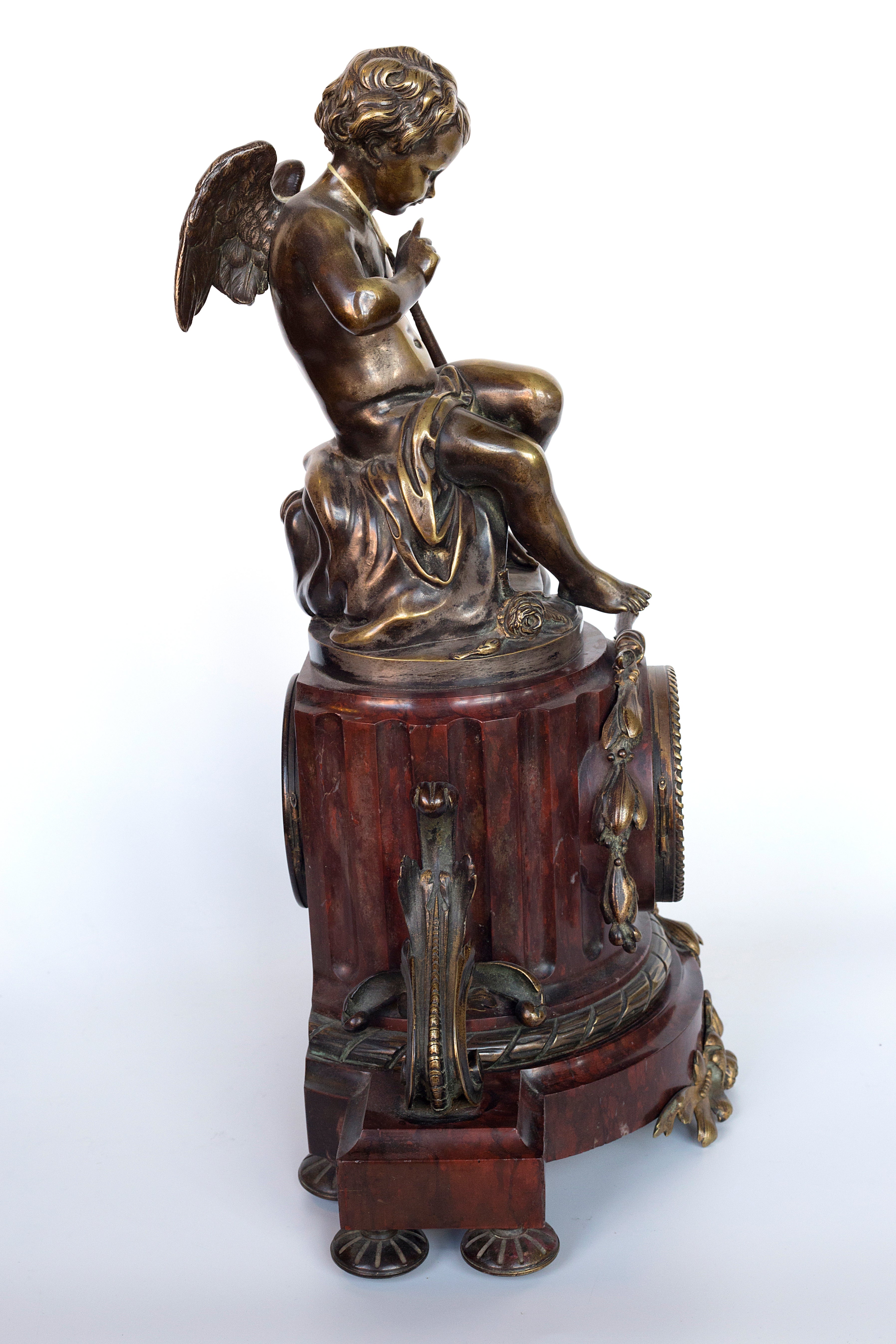Antique handcrafted bronze clock sits atop a stone plinth, featuring a sculpture of a Putti, inspired by the French Rococo sculptor Clodion (Claude Michel)