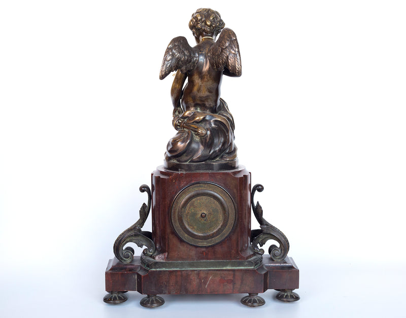 Antique handcrafted bronze clock sits atop a stone plinth, featuring a sculpture of a Putti, inspired by the French Rococo sculptor Clodion (Claude Michel)