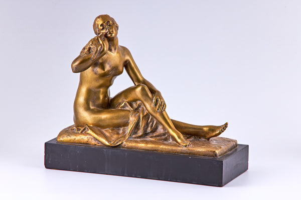 Una escultura de bronce bañada en oro de principios del siglo XX que representa a una mujer desnuda y un pájaro.