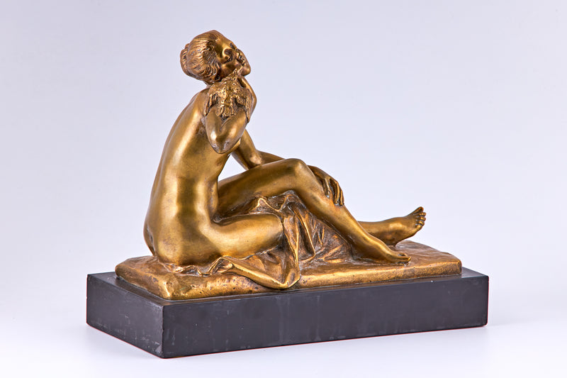 Una escultura de bronce bañada en oro de principios del siglo XX que representa a una mujer desnuda y un pájaro.