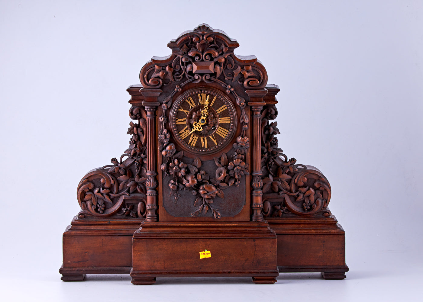 Reloj de nogal tallado a mano con números romanos en la esfera y decorado con motivos florales tallados