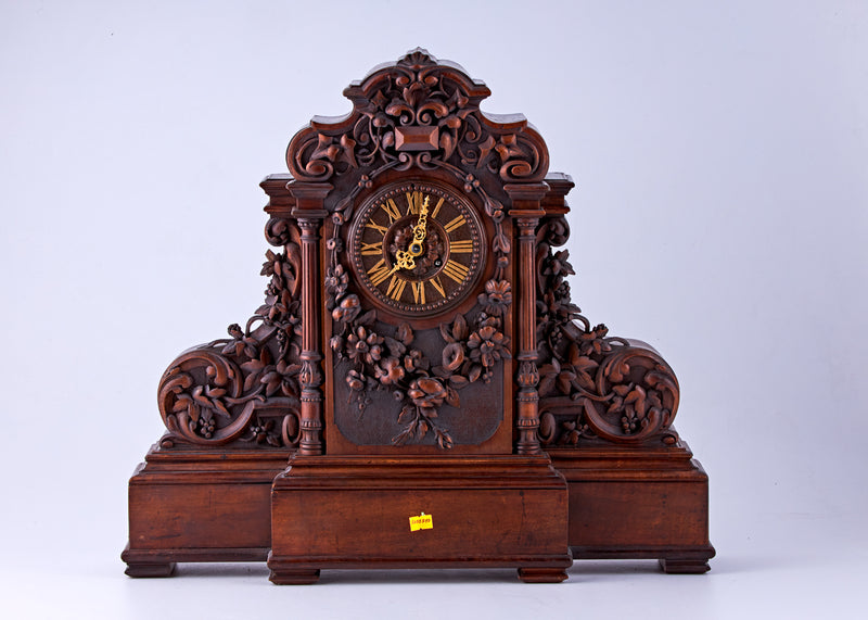 Hand-carved walnut clock with Roman numerals on the dial and decorated with carved floral motifs