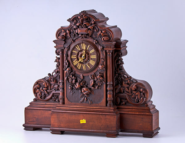 Hand-carved walnut clock with Roman numerals on the dial and decorated with carved floral motifs