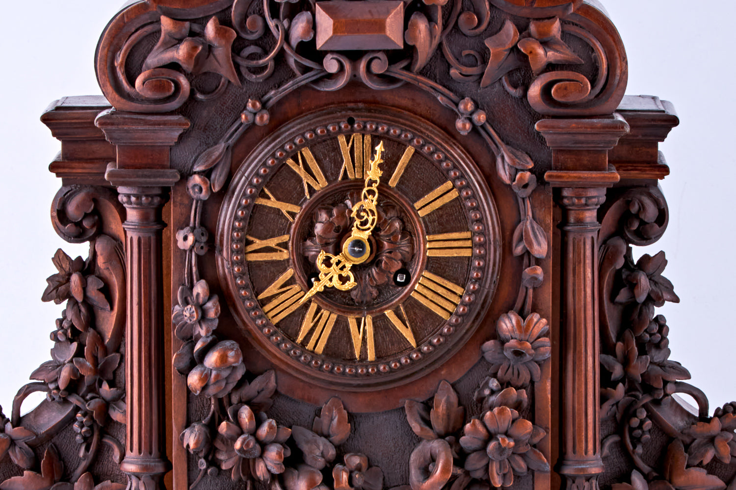 Reloj de nogal tallado a mano con números romanos en la esfera y decorado con motivos florales tallados